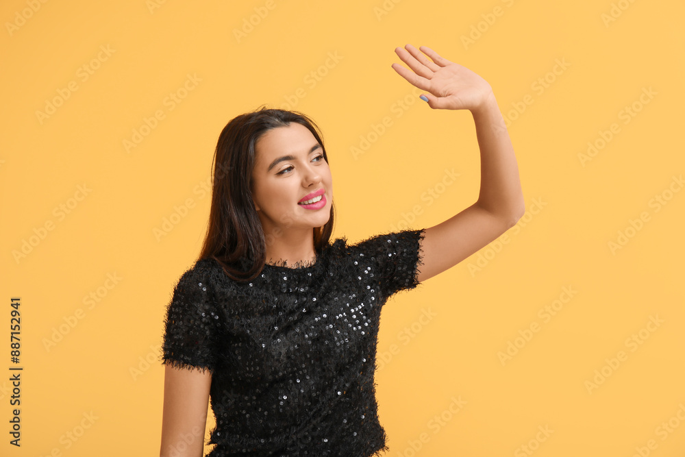 Beautiful young happy woman waving hand on yellow background Beautiful young happy woman waving hand on yellow background