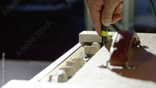 �Musician plugs his guitar into an amplifier and adjusts the dials.�