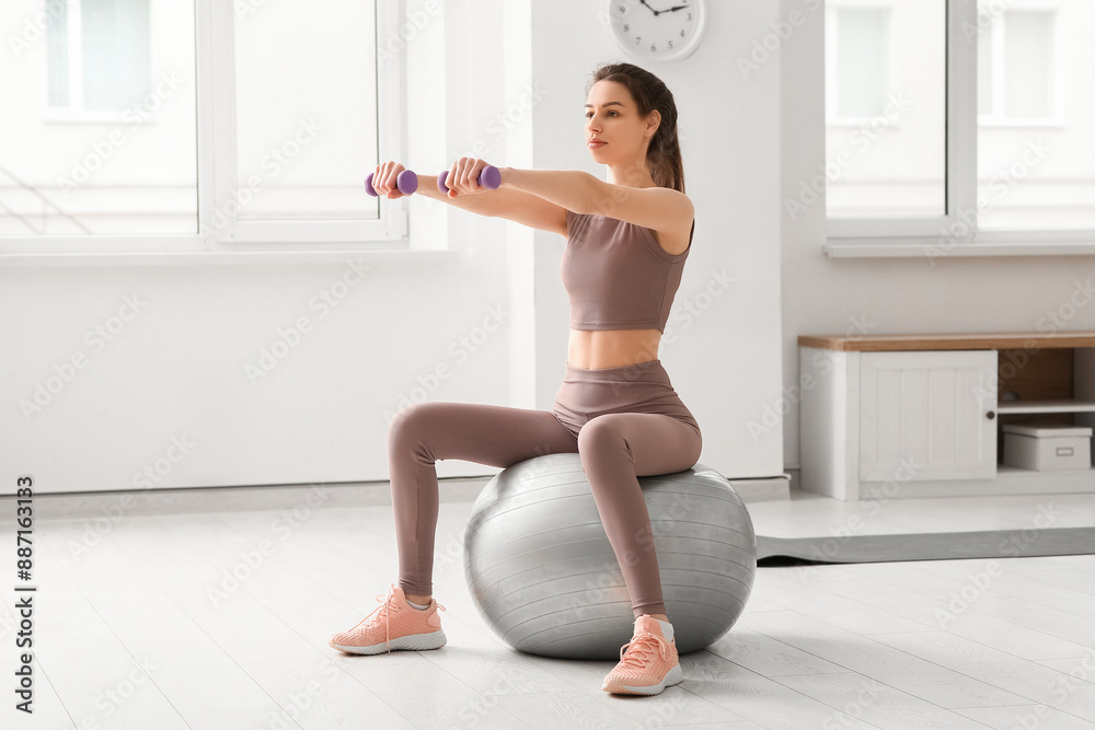 Beautiful young sporty woman with dumbbells and fitness ball training at home Beautiful young sporty woman with dumbbells and fitness ball training at home