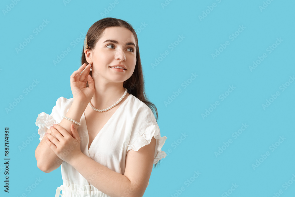 Beautiful young woman with pearl accessories on blue background Beautiful young woman with pearl accessories on blue background