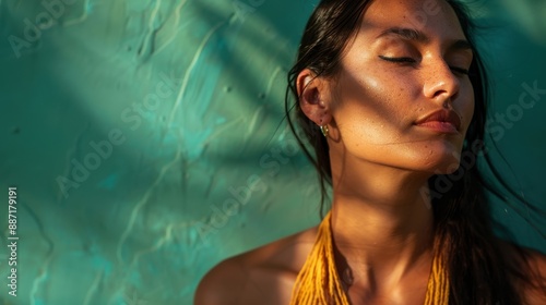 Close-up of a woman's face with sun-kissed skin, eyes closed and relaxed, with a teal background.