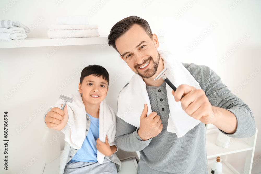 Obraz premium Happy father and his little son holding razors with towels in bathroom