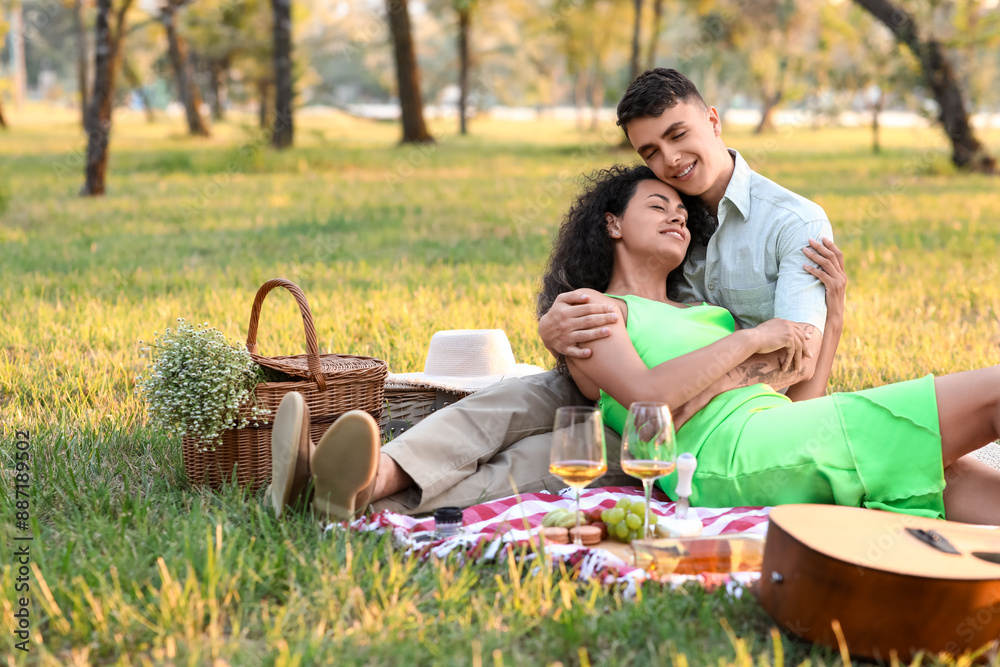 Beautiful young happy couple with glasses of wine having romantic picnic in park Beautiful young happy couple with glasses of wine having romantic picnic in park
