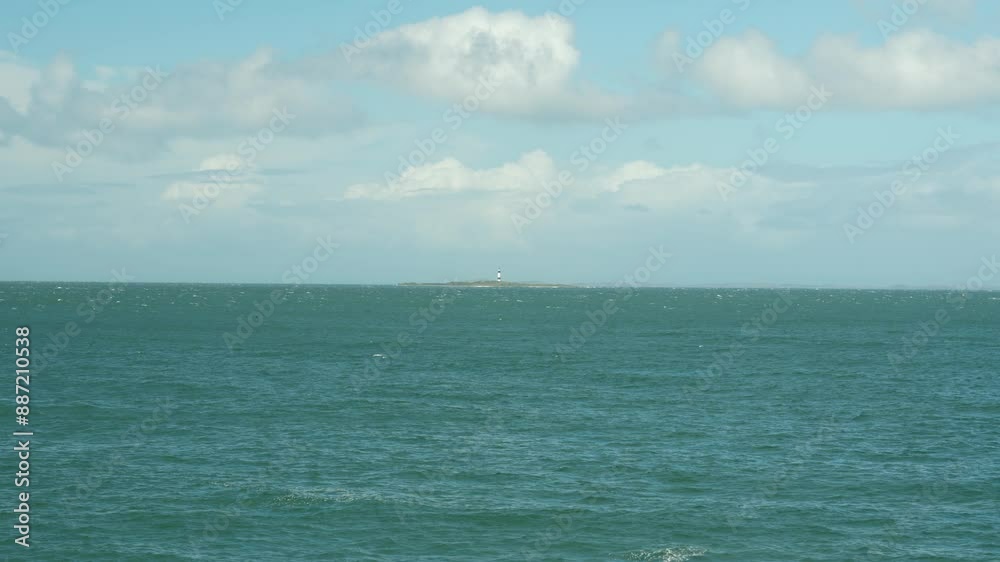 Scenic view of Tiwai Point with a distant lighthouse across the calm ocean waters under a partly cloudy sky. Remote and serene coastal landscape Scenic view of Tiwai Point with a distant lighthouse across the calm ocean waters under a partly cloudy sky. Remote and serene coastal landscape