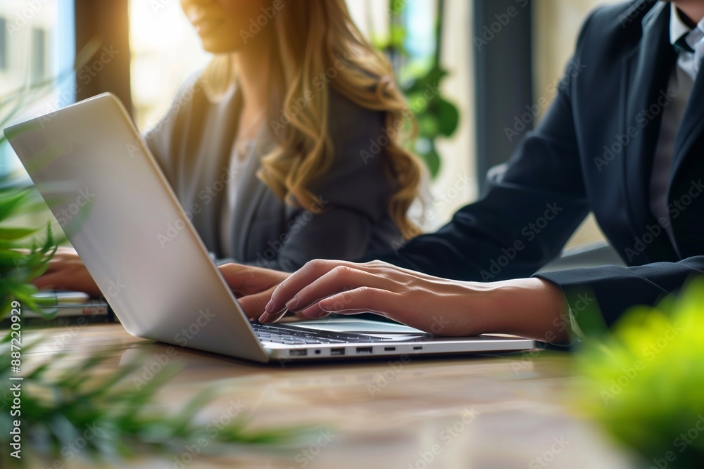 Two business people, a man and a woman, working together using a laptop computer while sitting at a desk in an office. The business concept photo for tech and copy space. Two business people, a man and a woman, working together using a laptop computer while sitting at a desk in an office. The business concept photo for tech and copy space.