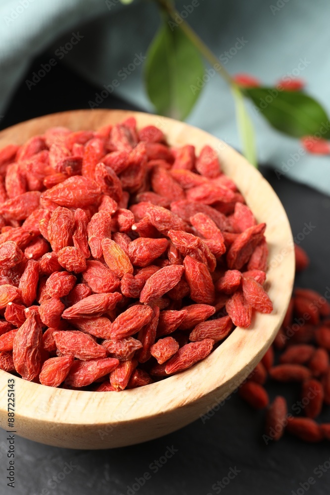 Dried goji berries in bowl on dark textured table, closeup Dried goji berries in bowl on dark textured table, closeup