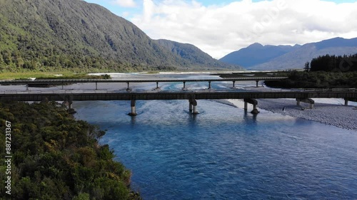 aerial panorama of taramakau river and stanley gooseman bridge near arthur's pass village in southern alps, canterbury, new zealand south island; railway bridge crossing turquoise river in mountains photo