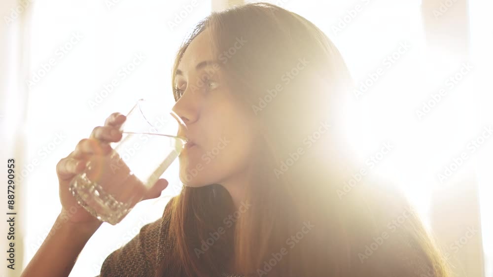girl drinks water. the problem is the lack of clean drinking water in the world. healthy eating concept. cute girl drinks water from a glass glass sun against the background of a window in kitchen girl drinks water. the problem is the lack of clean drinking water in the world. healthy eating concept. cute girl drinks water from a glass glass sun against the background of a window in kitchen