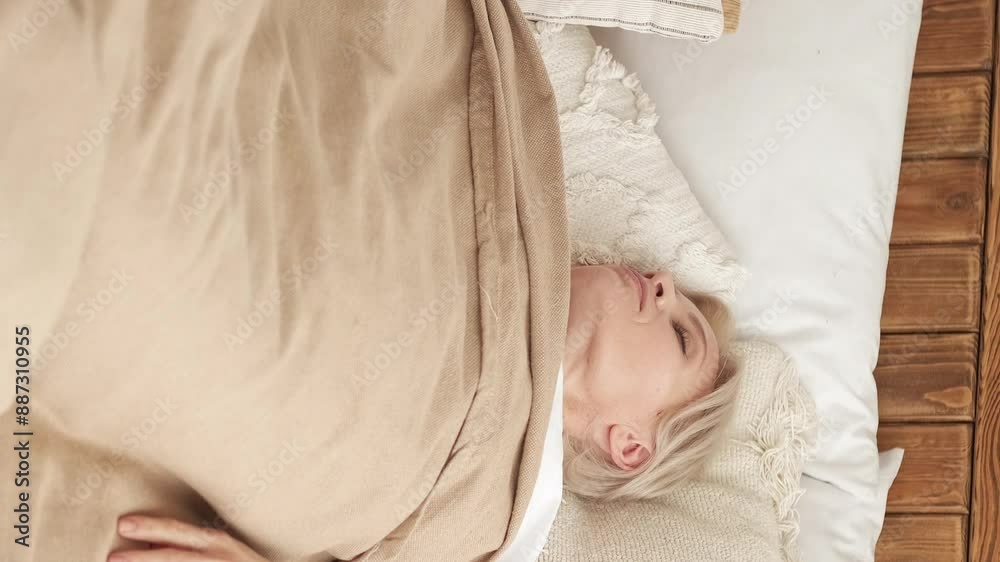 Vertical video. Leisure morning. Sleeping resting. Wonderful rest. Relaxed woman covered with blanket enjoying free time laying in comfortable bed at home. Vertical video. Leisure morning. Sleeping resting. Wonderful rest. Relaxed woman covered with blanket enjoying free time laying in comfortable bed at home.