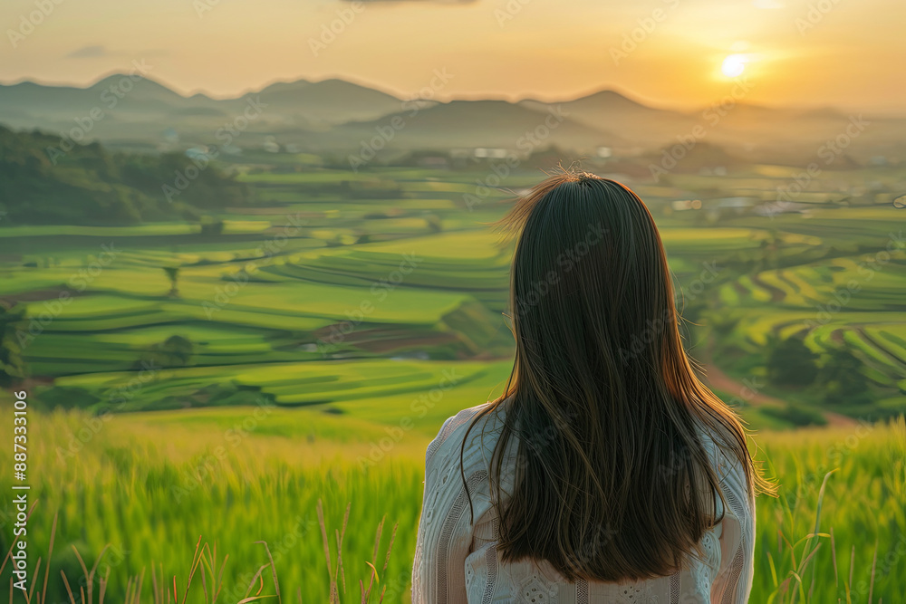 Asian woman overlooking green fields at sunset Asian woman overlooking green fields at sunset