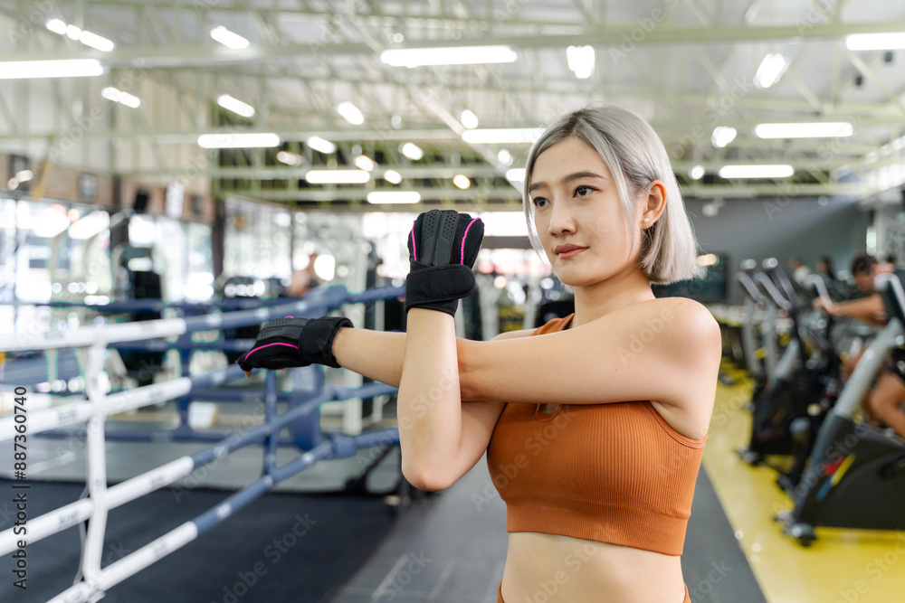 Young woman stretching her arms and upper body before starting her morning work out at a local gym
