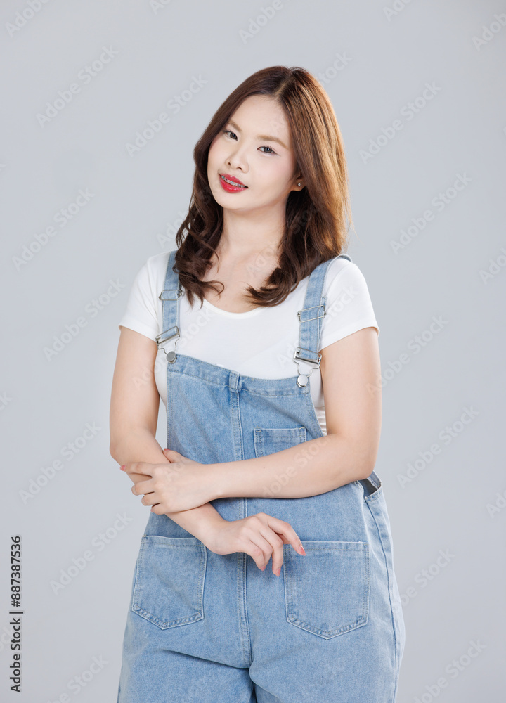 Portrait of Asian cute cheerful young girl wearing denim overalls, stylish model woman with happy and cool sweet smile standing posing isolated on white background, Teenage and youth fashion.