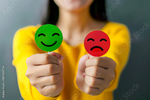 Contrasting Emotions: Hands Holding Red and Green Sad Face Icons for Feedback and Customer Satisfaction.
