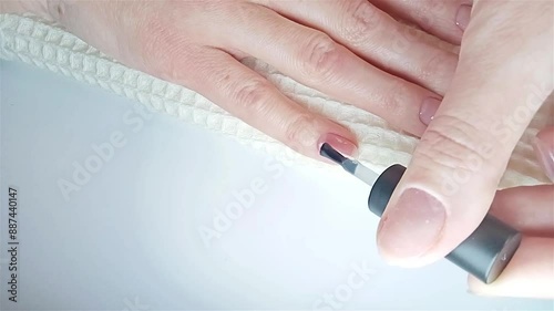 Gel polish manicure step-by-step guide. Step 7 Nails base coat. A woman applies a transparent gel base coat to the little finger of her right hand. At-home manicure photo