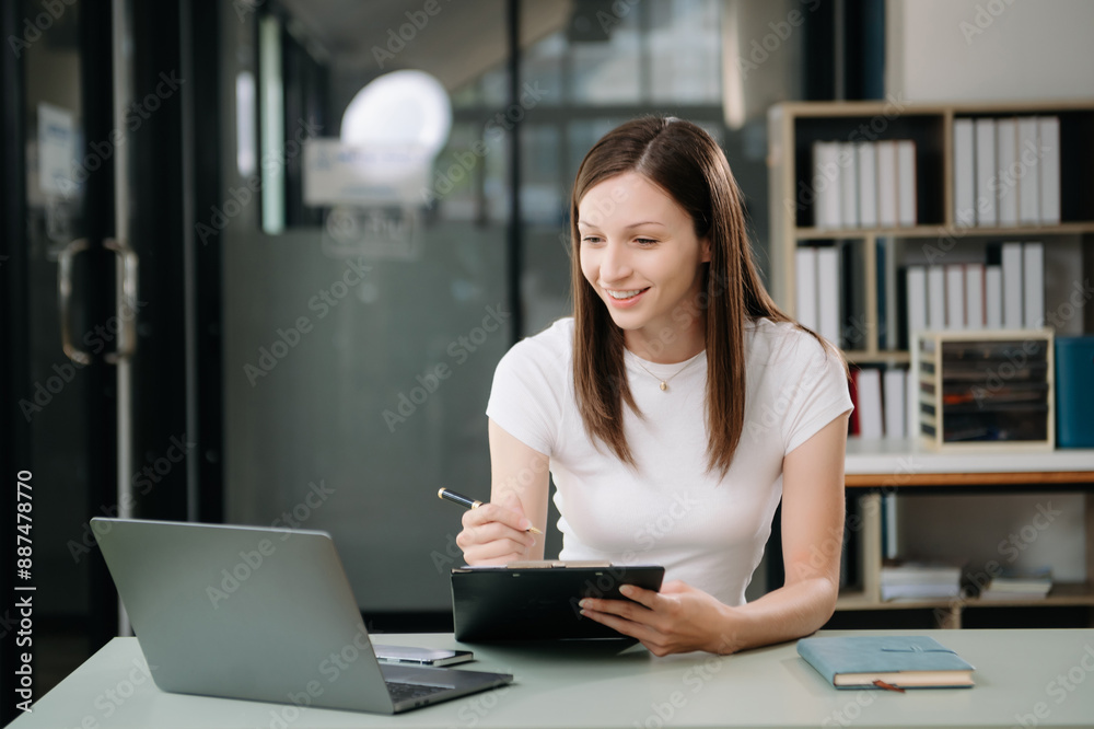 Fototapeta premium Beautiful woman using laptop and tablet while sitting at her working place. Concentrated