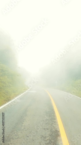 Misty foggy road high quality 4K slow motion vertical stories format footage, POV car driving high in mountain clouds, Northern Thailand.