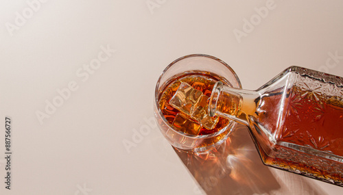 Whiskey is poured into a glass with ice photo