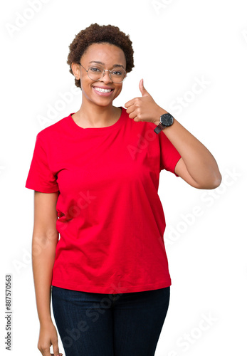 Beautiful young african american woman wearing glasses over isolated background doing happy thumbs up gesture with hand. Approving expression looking at the camera showing success.