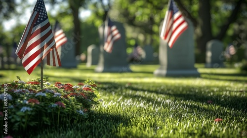 American flags placed at graves in a cemetery with green grass and flowers.