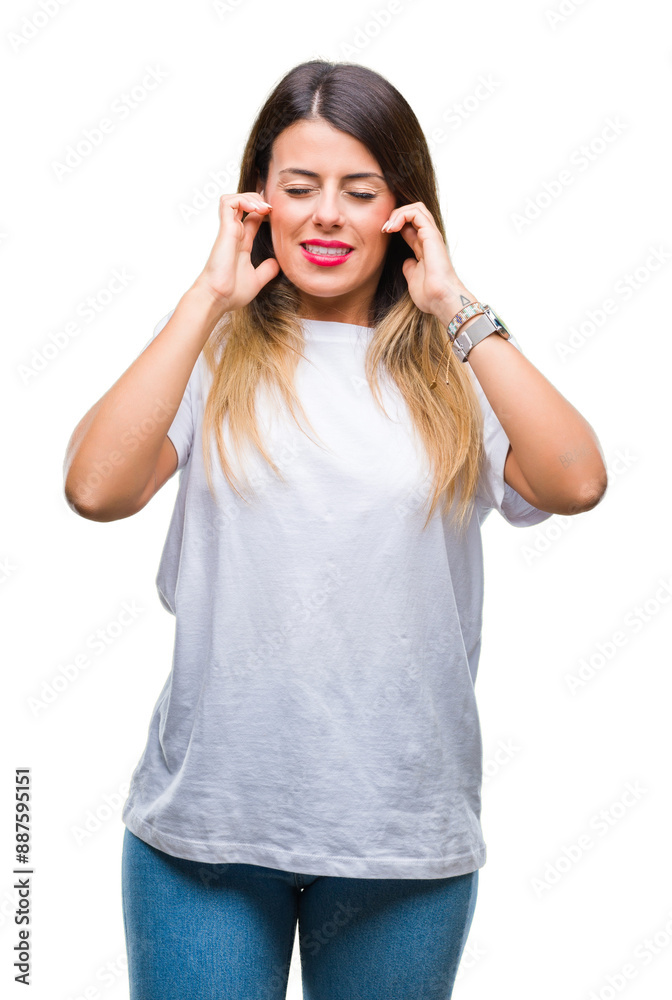Young beautiful woman casual white t-shirt over isolated background covering ears with fingers with annoyed expression for the noise of loud music. Deaf concept. Young beautiful woman casual white t-shirt over isolated background covering ears with fingers with annoyed expression for the noise of loud music. Deaf concept.