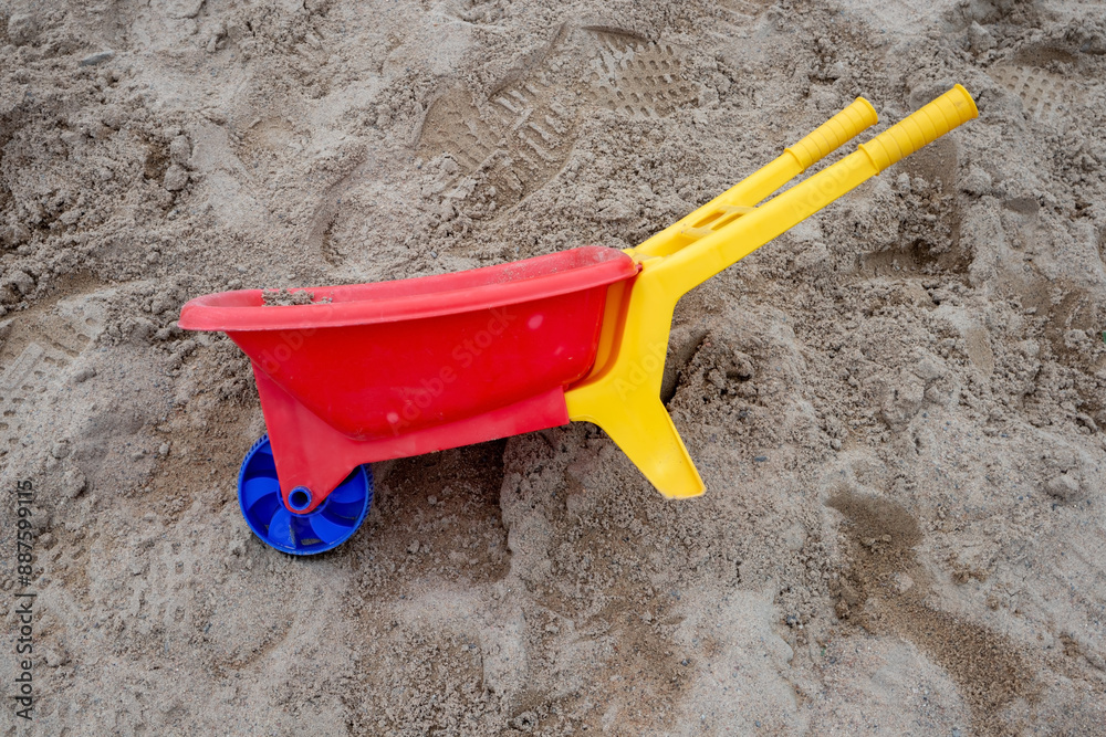 plastic toy wheelbarrow in a sandbox outdoors plastic toy wheelbarrow in a sandbox outdoors