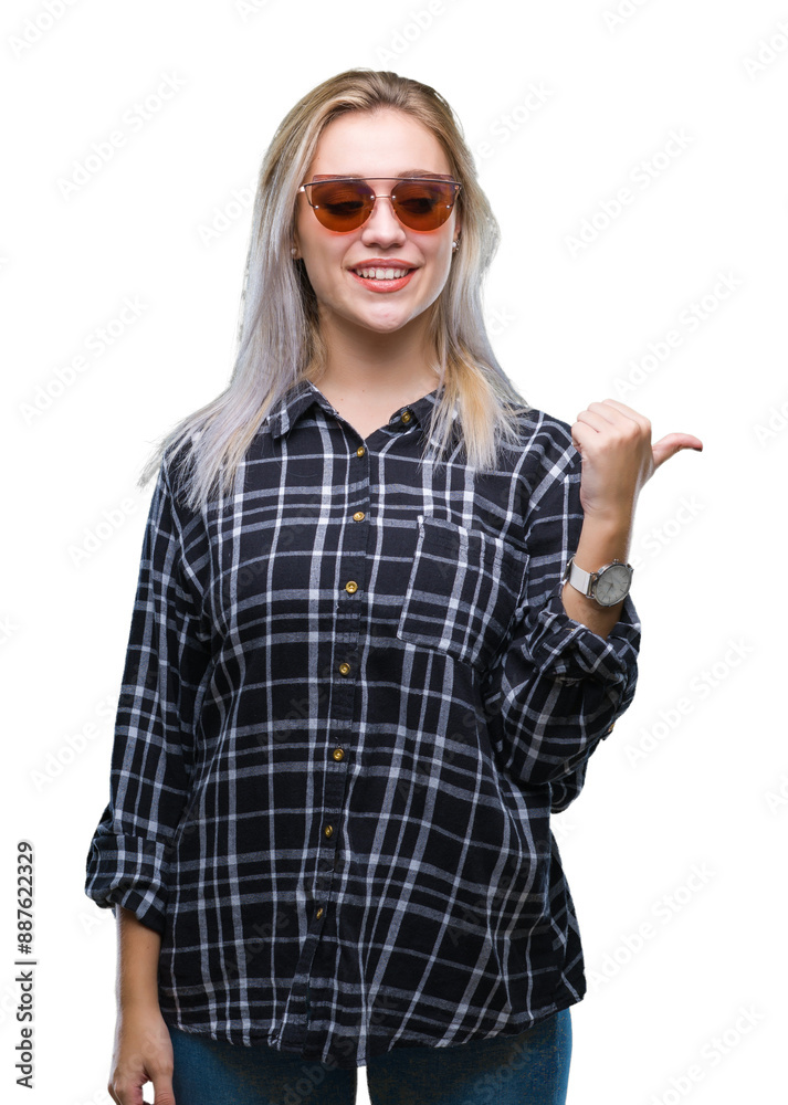 Obraz premium Young blonde woman wearing sunglasses over isolated background smiling with happy face looking and pointing to the side with thumb up.