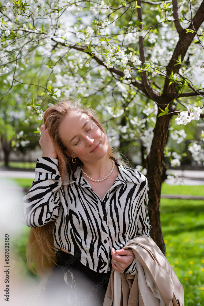 Young happy woman in spring near blooming trees