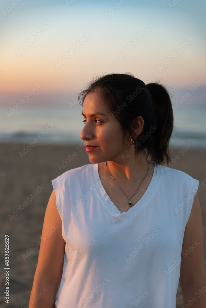 Woman contemplates the sunrise from the beach with a smile. Woman contemplates the sunrise from the beach with a smile.