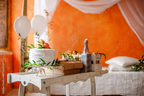 White cake with orange garnish on a table in a room with orange walls photo