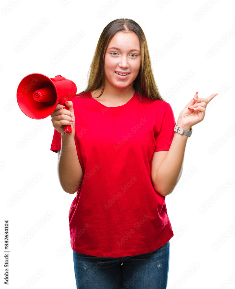 Young caucasian woman yelling through megaphone over isolated background very happy pointing with hand and finger to the side Young caucasian woman yelling through megaphone over isolated background very happy pointing with hand and finger to the side