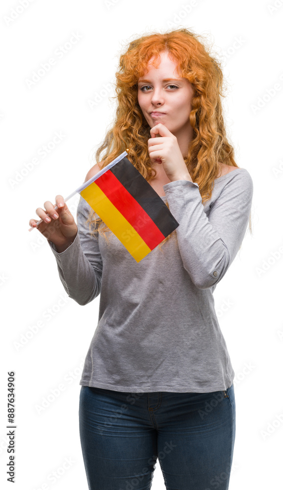 Young redhead woman holding flag of Germany serious face thinking about question, very confused idea