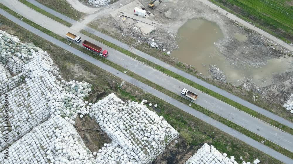 Garbage junkyard with white dump piles and transportation trucks. Aerial orbit shoot Garbage junkyard with white dump piles and transportation trucks. Aerial orbit shoot