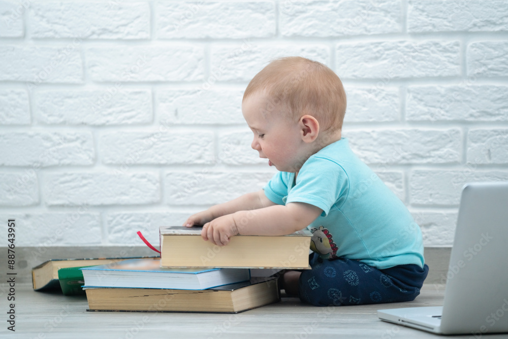 Funny portrait of little baby looks at a books. Intellectual development of newborns. Horizontal image.