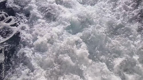 Looking down at white splashing swirls on blue sea water surface from the the sailing ship photo