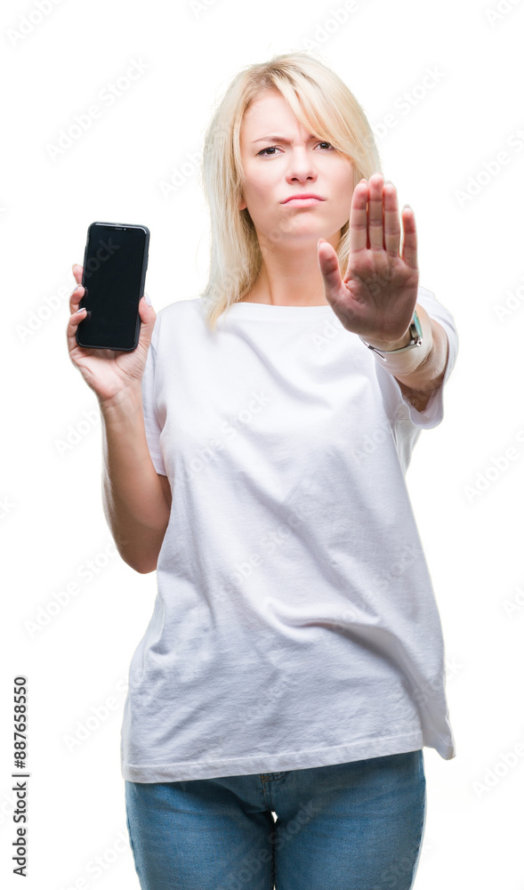 Young beautiful blonde woman showing screen of smartphone over isolated background with open hand doing stop sign with serious and confident expression, defense gesture