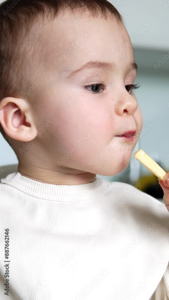 Beautiful child eating porridge from spoon. Cute little boy grabs a piece of cheese and takes a bite. Close up. Vertical video Beautiful child eating porridge from spoon. Cute little boy grabs a piece of cheese and takes a bite. Close up. Vertical video
