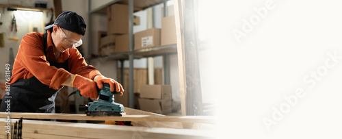 Female carpenter grinding wood plank with electric sander machine in carpentry workshop. Woman polishes wooden board