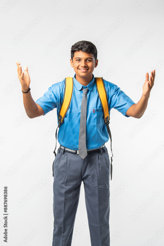 Indian Asian school boy in uniform with giving thumbs up, celebrating success or pointing to blank Indian Asian school boy in uniform with giving thumbs up, celebrating success or pointing to blank
