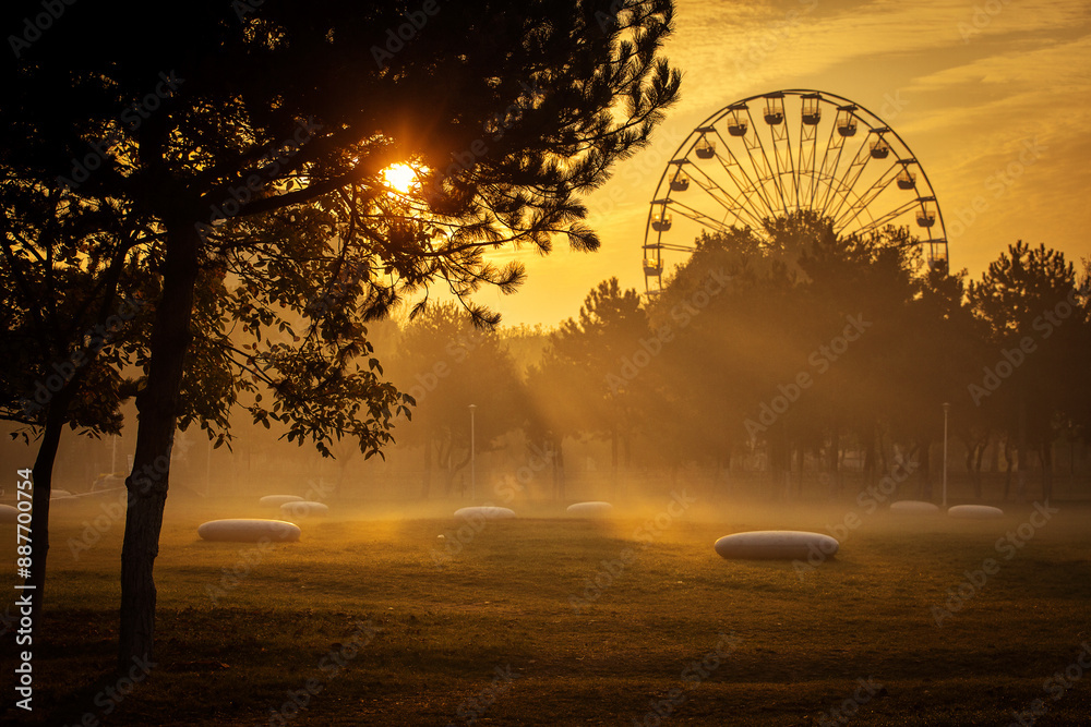 Beautiful autumn morning in a park with entertainment wheel in background