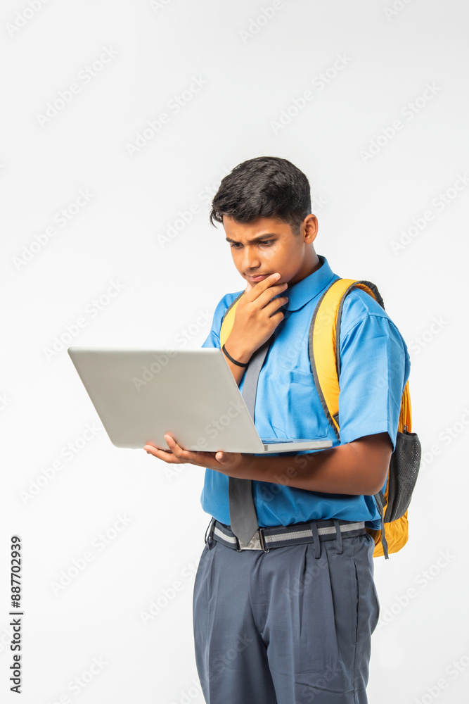 Indian Asian student in school uniform, holding laptop, isolated on white background, education concept Indian Asian student in school uniform, holding laptop, isolated on white background, education concept