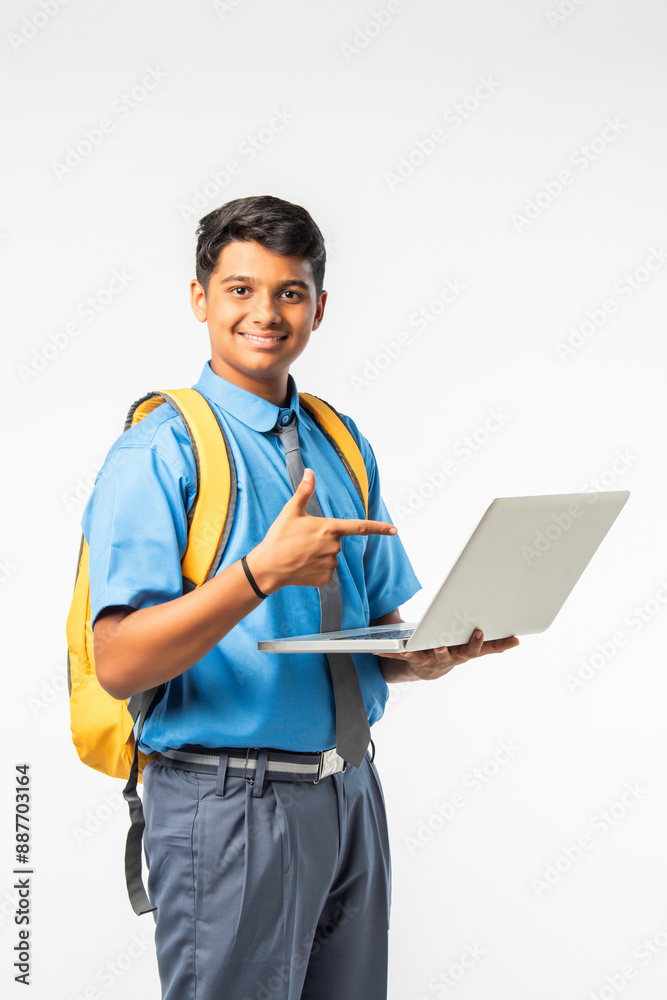 Indian Asian school boy in uniform with giving thumbs up, celebrating success or pointing to blank Indian Asian school boy in uniform with giving thumbs up, celebrating success or pointing to blank