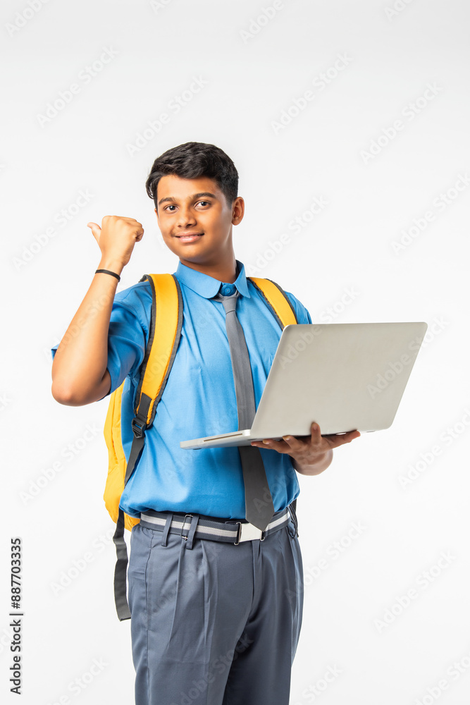 Indian Asian school boy in uniform with giving thumbs up, celebrating success or pointing to blank Indian Asian school boy in uniform with giving thumbs up, celebrating success or pointing to blank
