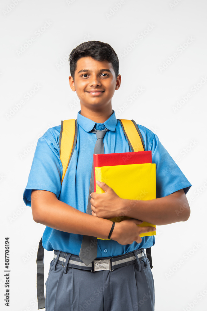 Indian Asian school boy in uniform with books or laptop and backpack, smiling and isolated Indian Asian school boy in uniform with books or laptop and backpack, smiling and isolated