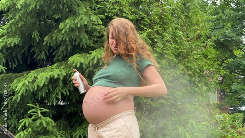 Young pregnant woman suffering of mosquito, insects and using mosquito spray at nature photo