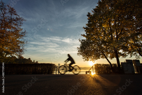 Obraz na płótnie Man biking in a park at sunrise with beautiful autumn colors and lake in background w salonie