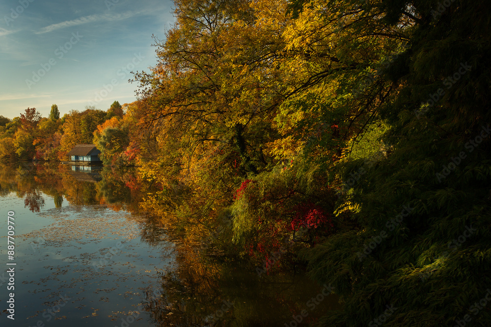 Landscape with beautiful house on a lake with colourful leafs in autumn season
