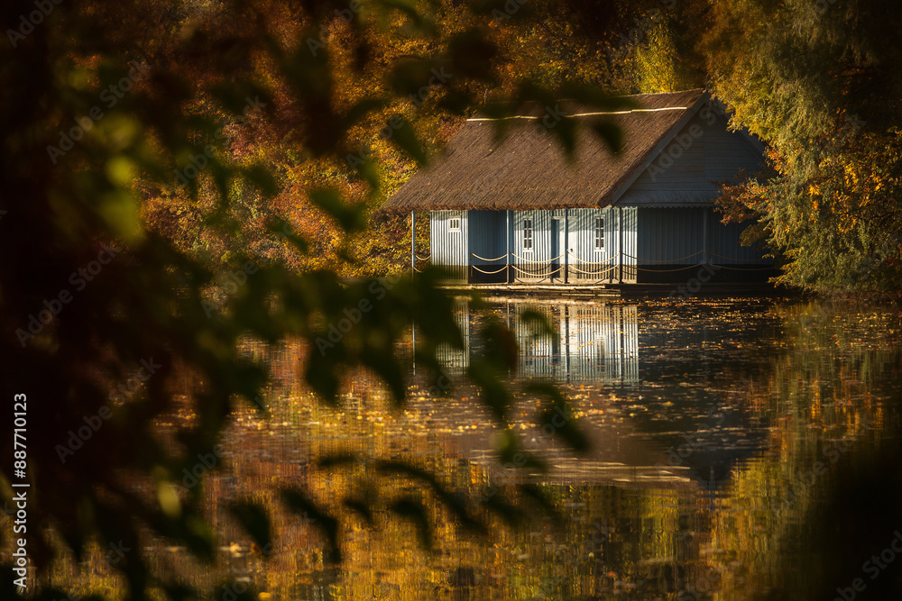 Landscape with beautiful house on a lake with colourful leafs in autumn season