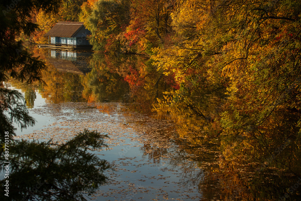 Landscape with beautiful house on a lake with colourful leafs in autumn season
