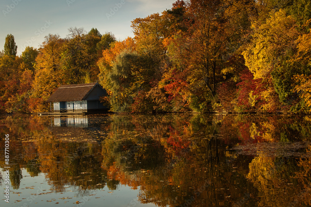 Landscape with beautiful house on a lake with colourful leafs in autumn season