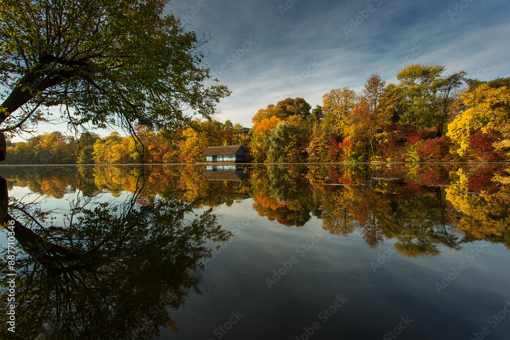 Landscape with beautiful house on a lake with colourful leafs in autumn season